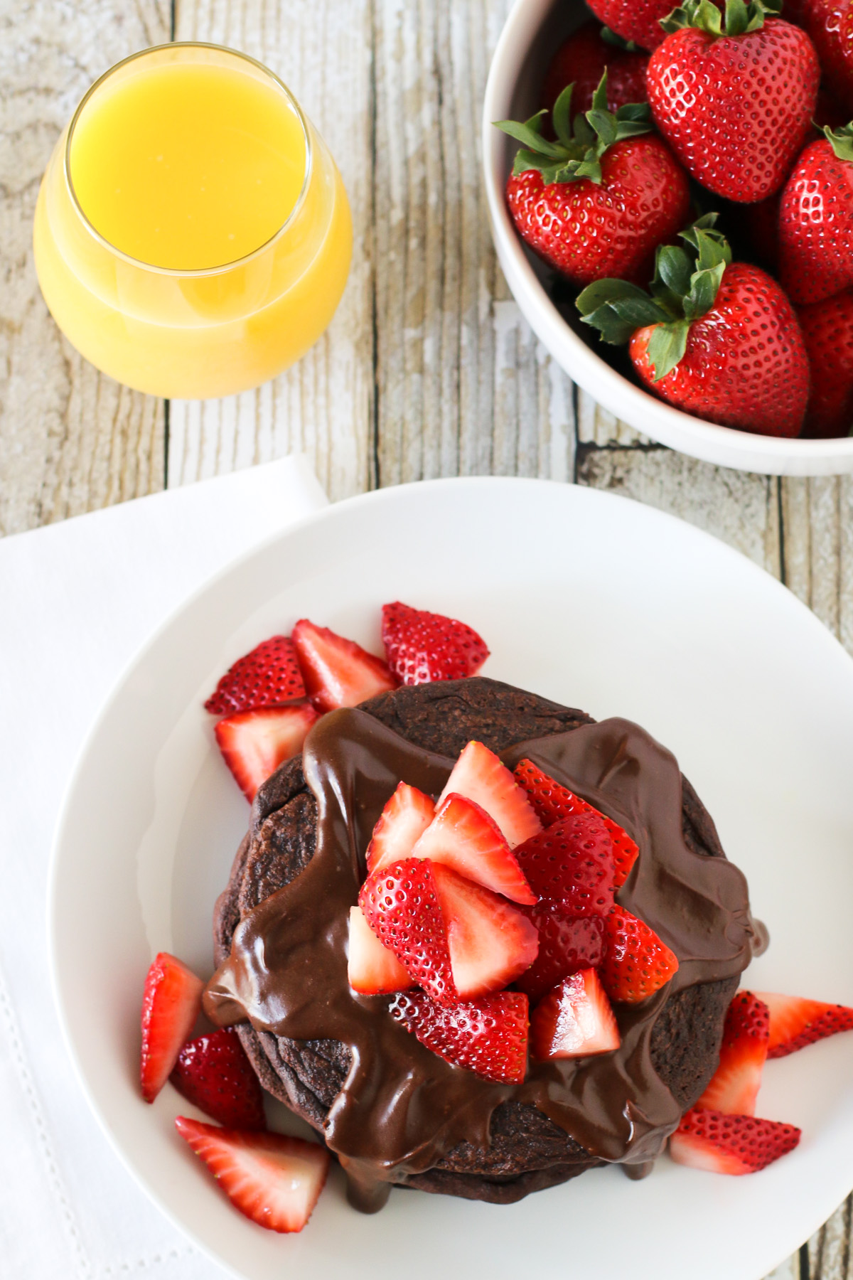 Gluten Free Vegan Double Chocolate Pancakes. Fluffy chocolate pancakes, covered in a simple chocolate sauce and fresh strawberries. Quite the decadent breakfast!