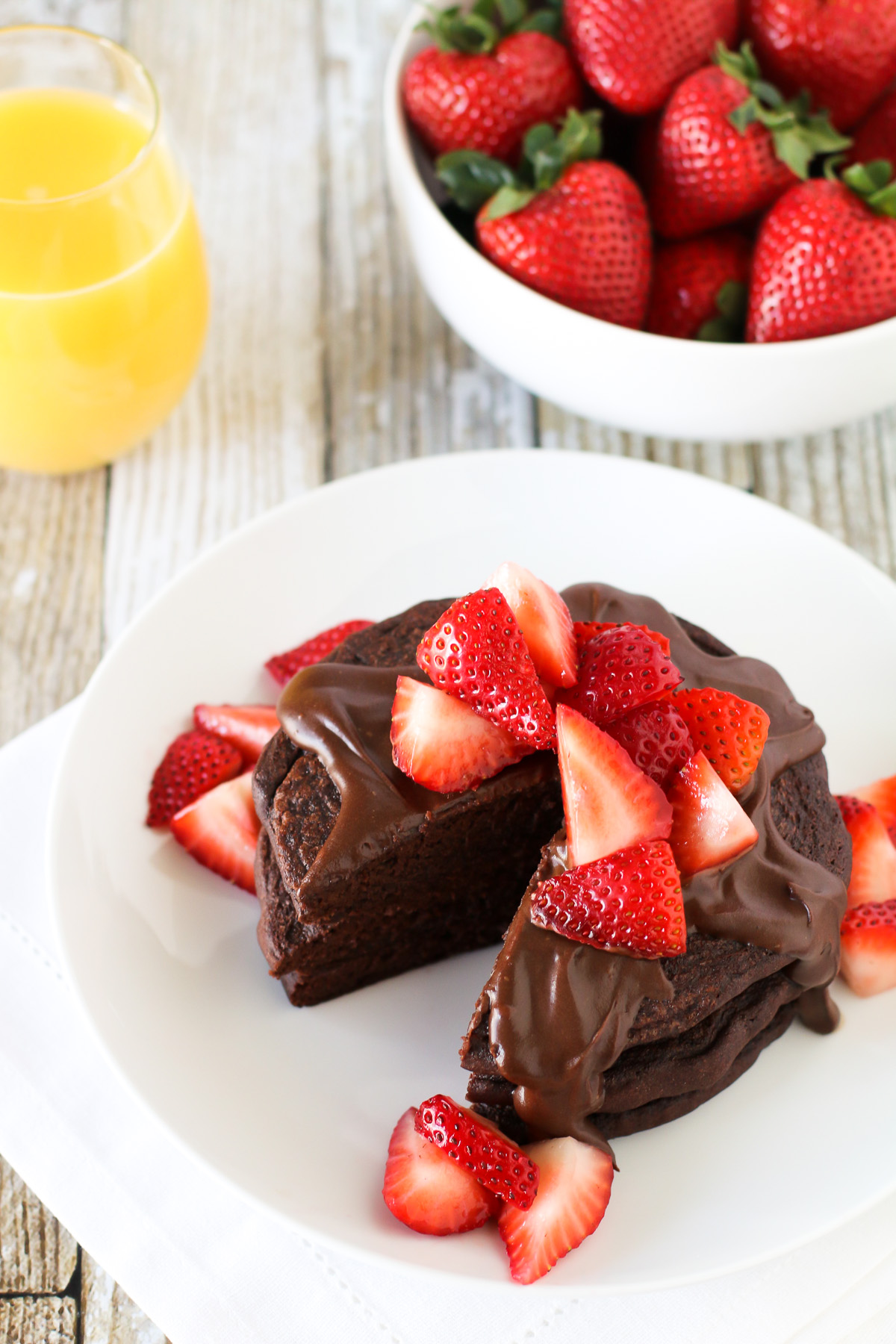 Gluten Free Vegan Double Chocolate Pancakes, featuring Bob’s Red Mill egg replacer. Fluffy chocolate pancakes, covered in a simple chocolate sauce and fresh strawberries. 