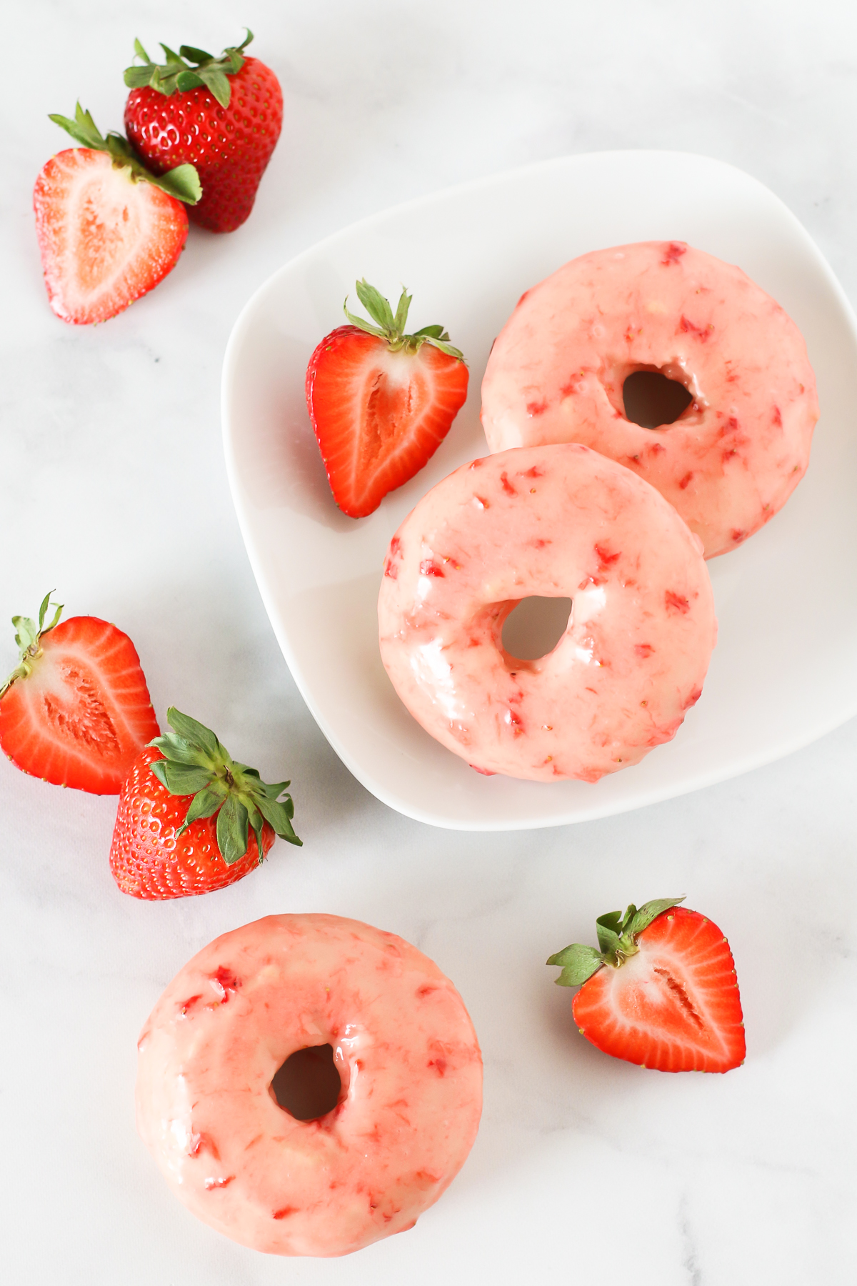 Gluten Free Vegan Baked Strawberry Donuts. Tender baked vanilla donuts with a fresh strawberry glaze. So pretty!