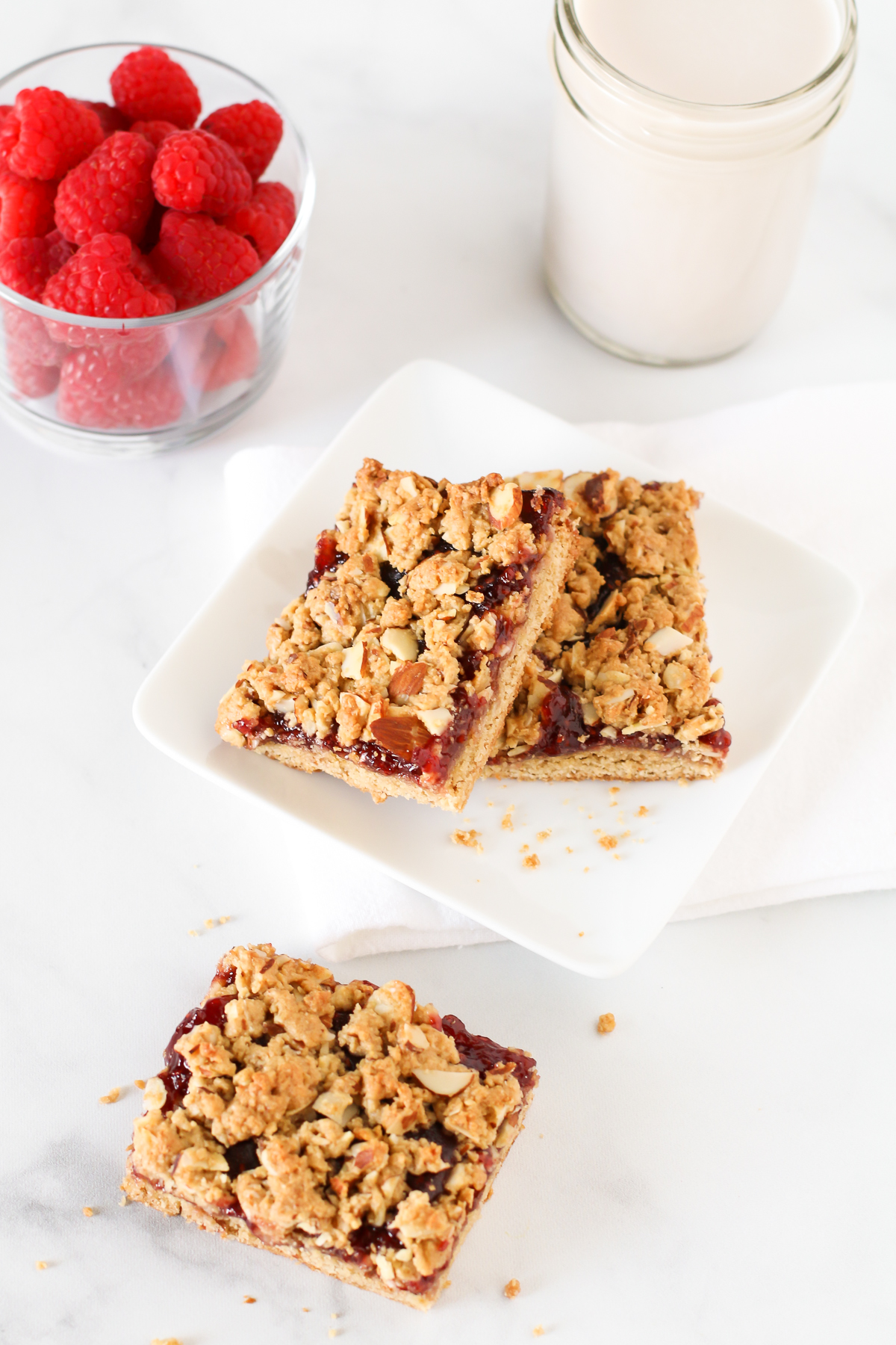 Gluten Free Vegan Raspberry Almond Breakfast Bars. These almond oat bars are slightly sweetened and filled with raspberry jam. A lovely on-the-go breakfast treat.