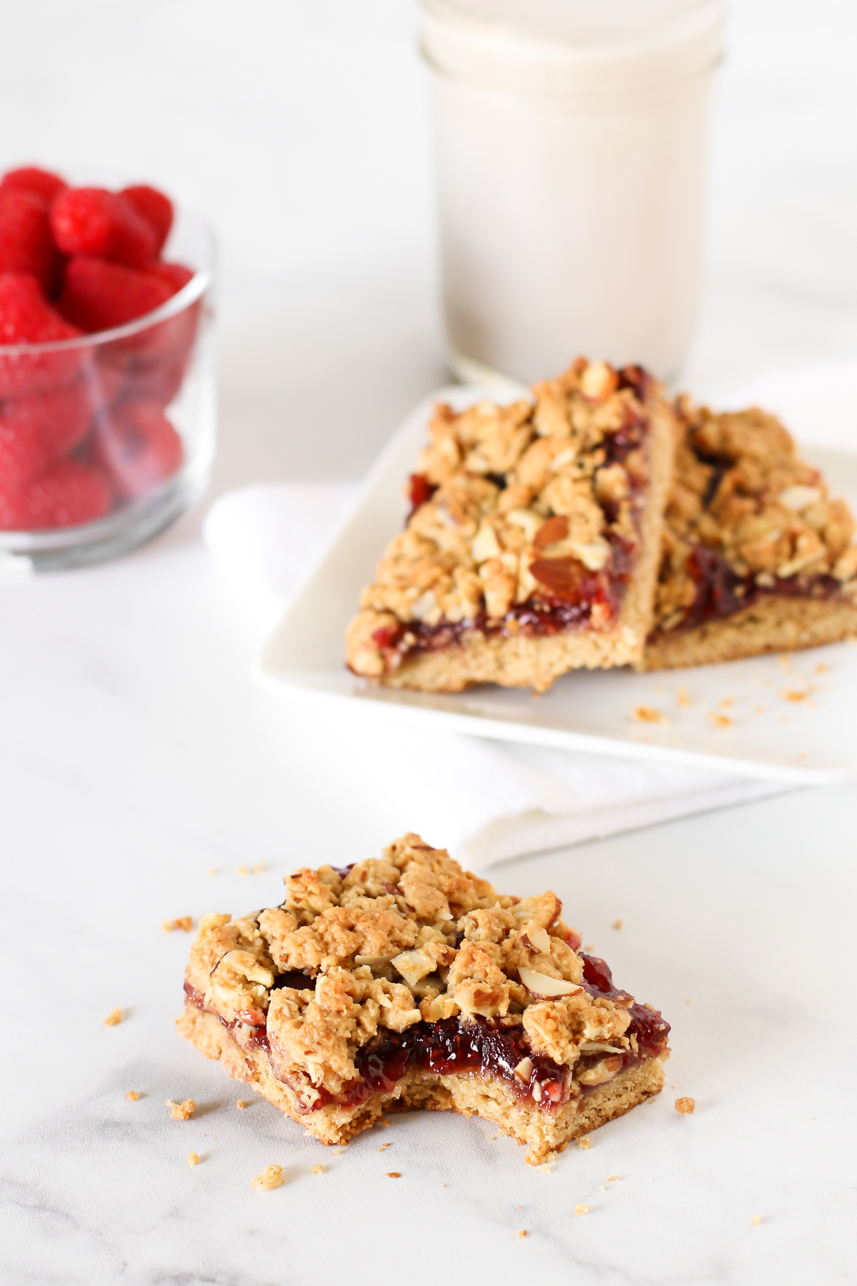 Gluten Free Vegan Raspberry Almond Breakfast Bars. These almond oat bars are slightly sweetened and filled with raspberry jam. A lovely on-the-go breakfast treat.