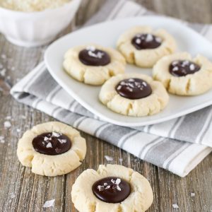 Gluten Free Vegan Salted Chocolate Almond Thumbprint Cookies. Soft almond thumbprint cookies, filled with a decadent chocolate ganache and topped with beautiful sea salt flakes.