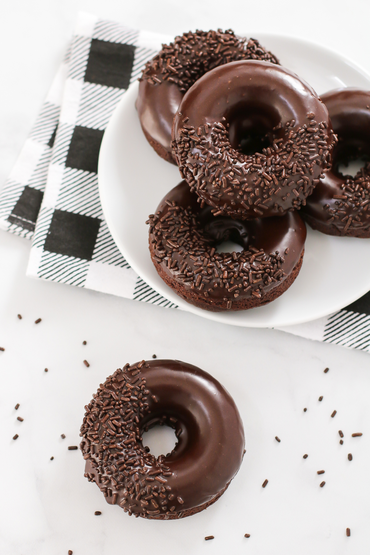 Gluten Free Vegan Baked Chocolate Donuts. Extra chocolatey cake donuts, dipped in a decadent chocolate glaze. Can’t forget the chocolate sprinkles!