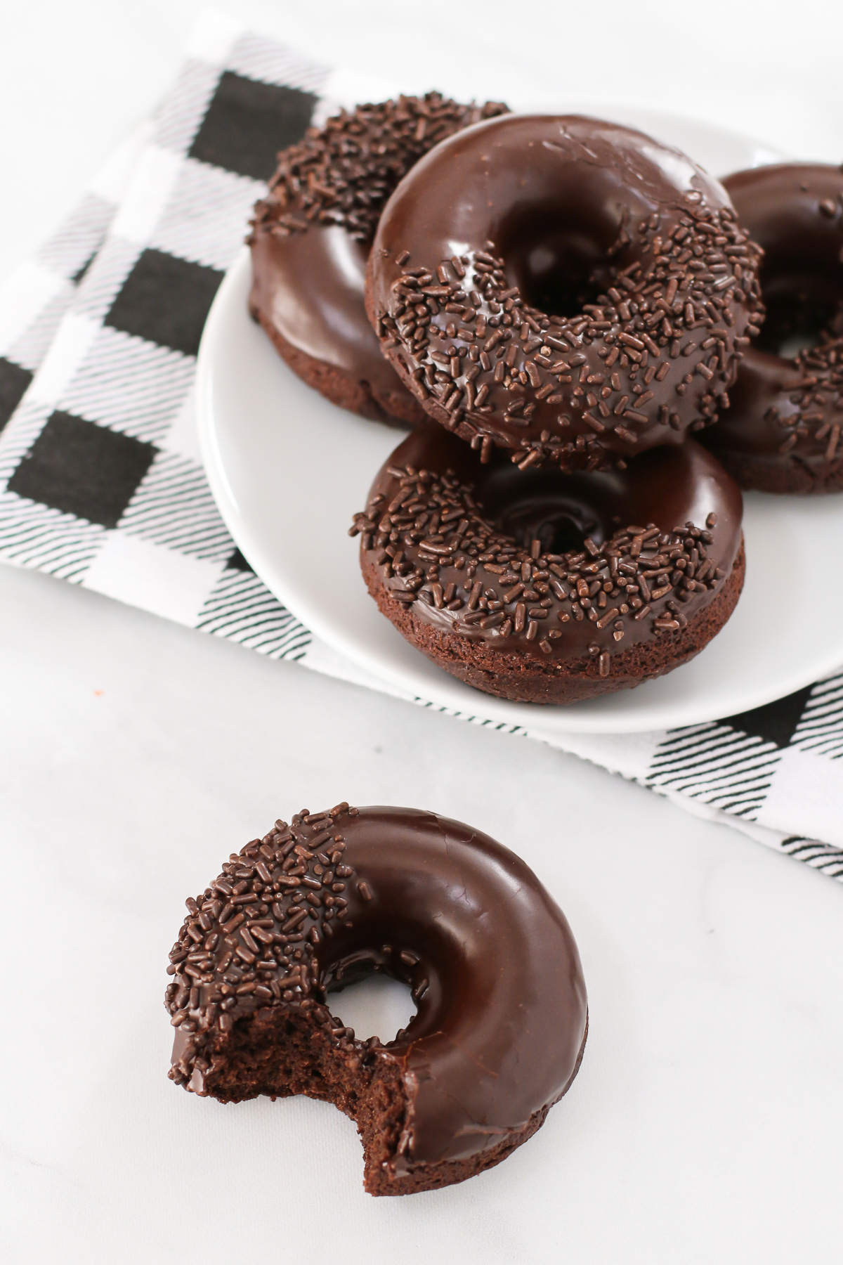 Gluten Free Vegan Baked Chocolate Donuts. Extra chocolatey cake donuts, dipped in a decadent chocolate glaze. Can’t forget the chocolate sprinkles!