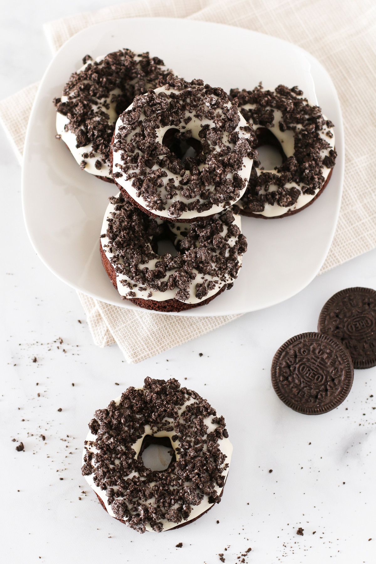 Gluten Free Vegan Cookies N’ Cream Donuts. Baked chocolate donuts with a vanilla glaze, covered with crushed Oreo cookies. Oh so tasty!