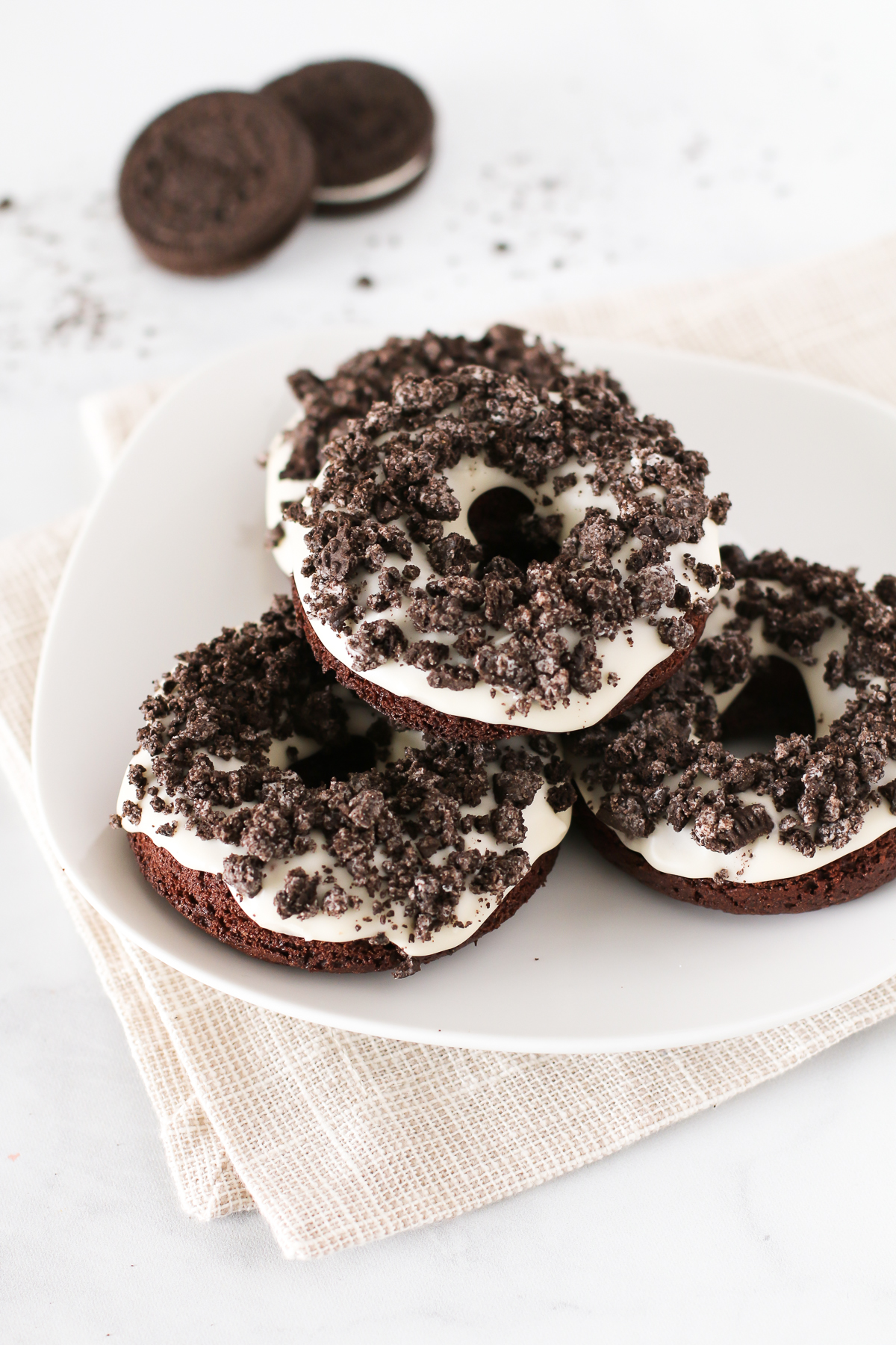 Gluten Free Vegan Cookies N’ Cream Donuts. Baked chocolate donuts with a vanilla glaze, covered with crushed Oreo cookies. Oh so tasty!